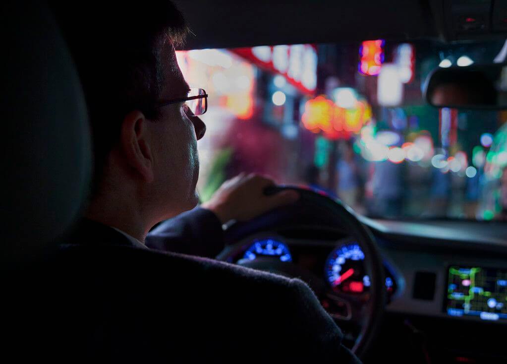 Szemüveges férfi éjszaka autót vezet