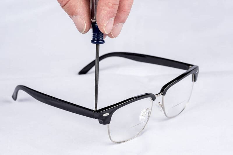 Csavarhúzóval szemüveg szárát csavarozza